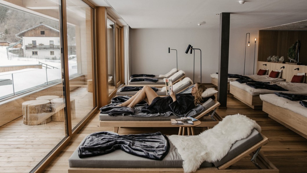 Una donna è distesa su una sdraio e legge una rivista.