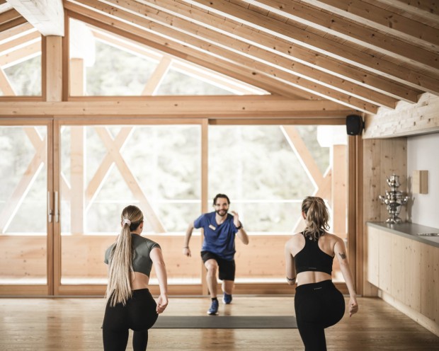 Due donne e un uomo fanno esercizio in una sala yoga