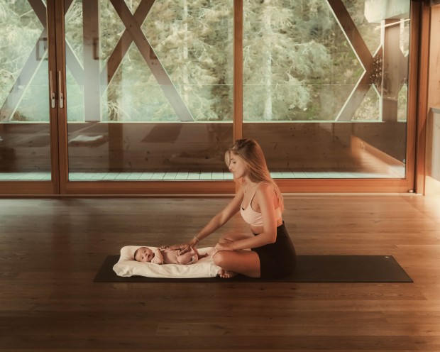 Una donna seduta con un bambino su un tappetino nello studio di yoga