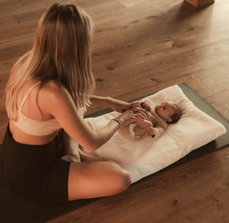 Una donna avvolge un bambino su un tappetino a terra