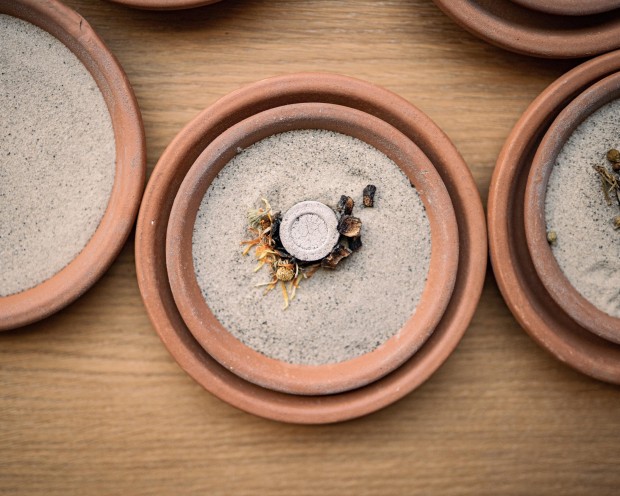 Ciotole di terracotta con erbe fumiganti su un tavolo di legno