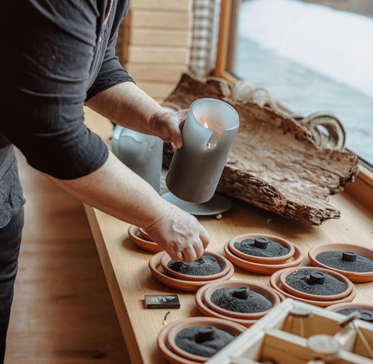 Una persona prepara ciotole con erbe fumiganti su un tavolo per una meditazione