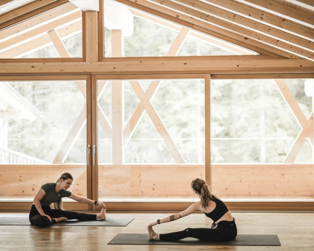 2 donne fanno stretching nella sala yoga con una grande finestra