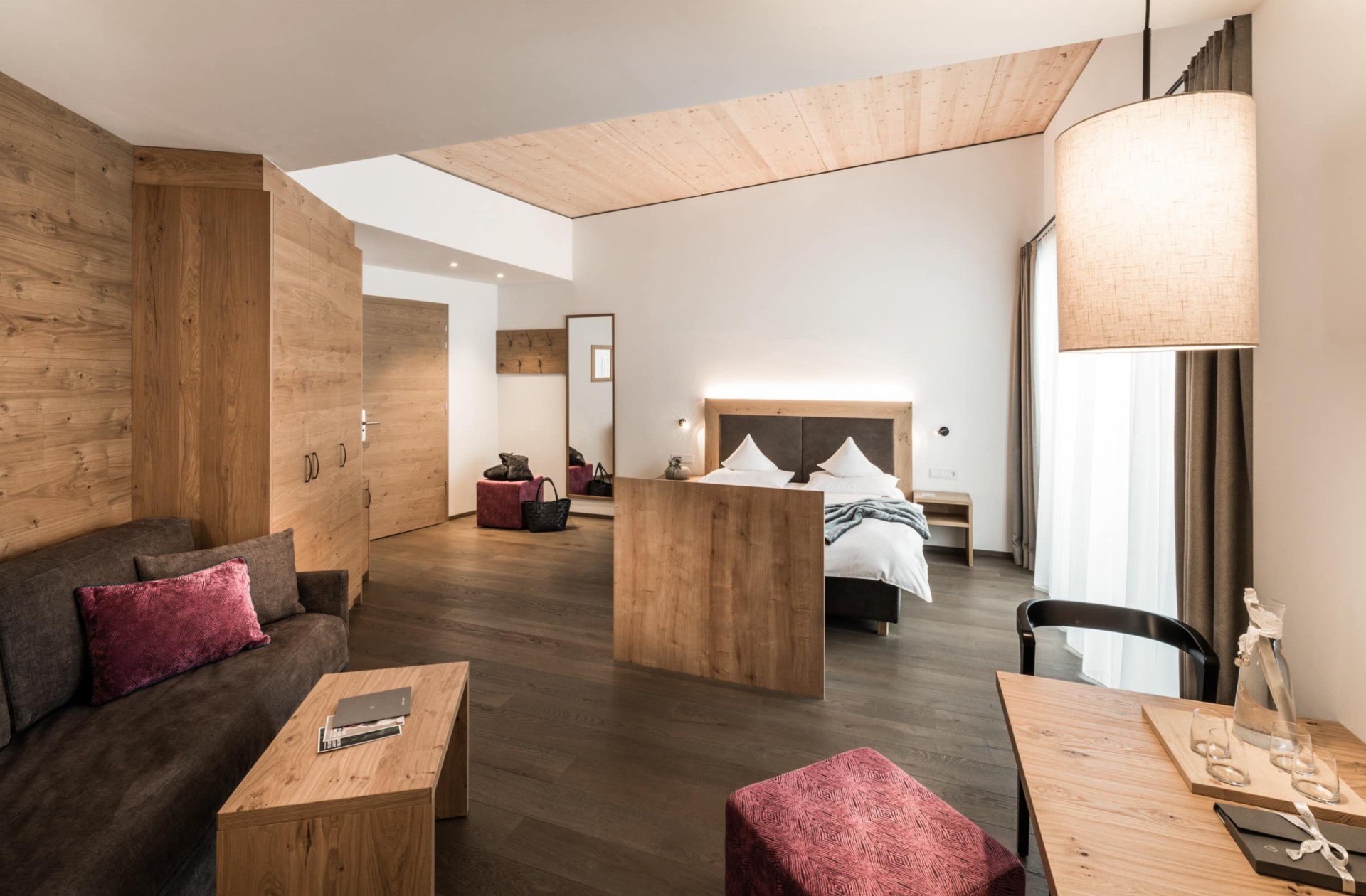 A spacious hotel room with wooden interiors, a cozy seating area, and a large bed.