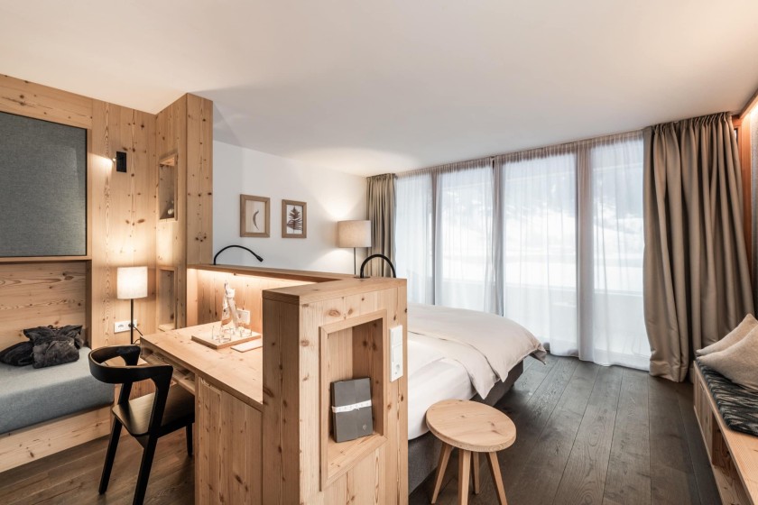 Una camera d'hotel elegante con mobili in legno moderni, una scrivania e illuminazione soffusa.