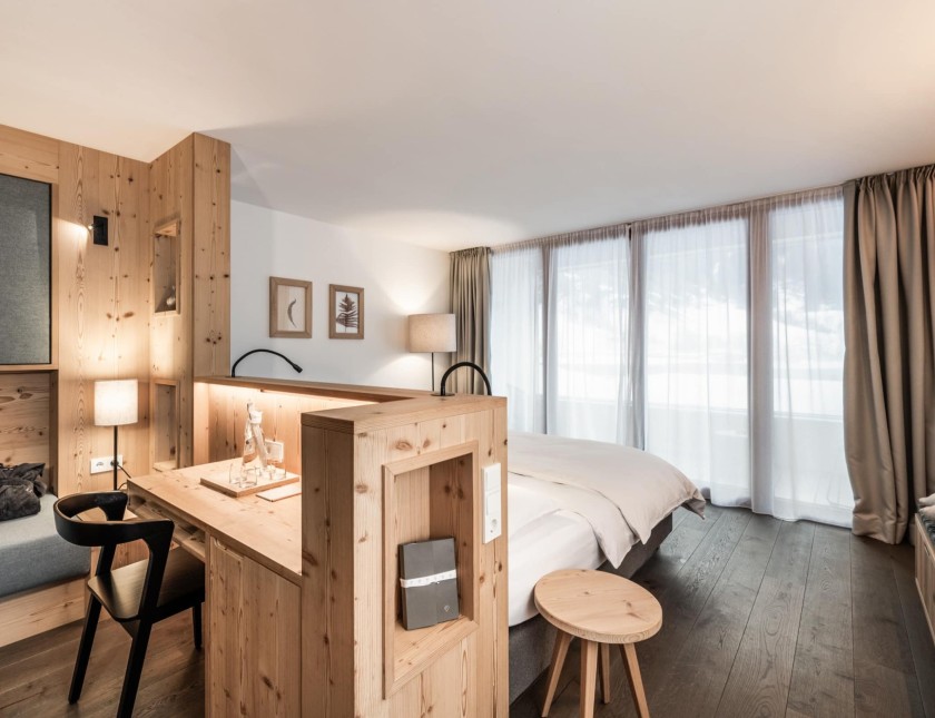 Una camera d'hotel elegante con mobili in legno moderni, una scrivania e illuminazione soffusa.