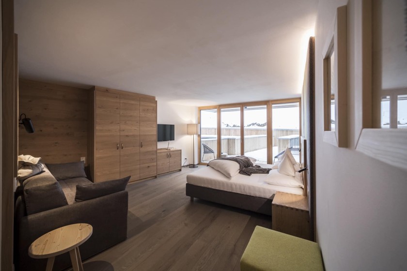 A modern and stylish hotel room with a large bed, wooden walls, and a balcony view.