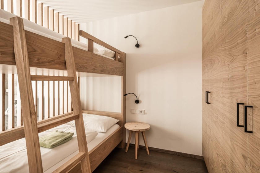 Letto a castello in legno in una cameretta con sgabello