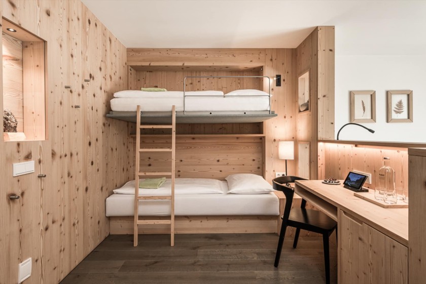 Una camera d'hotel adatta alle famiglie con un letto a castello in legno e un'atmosfera accogliente.