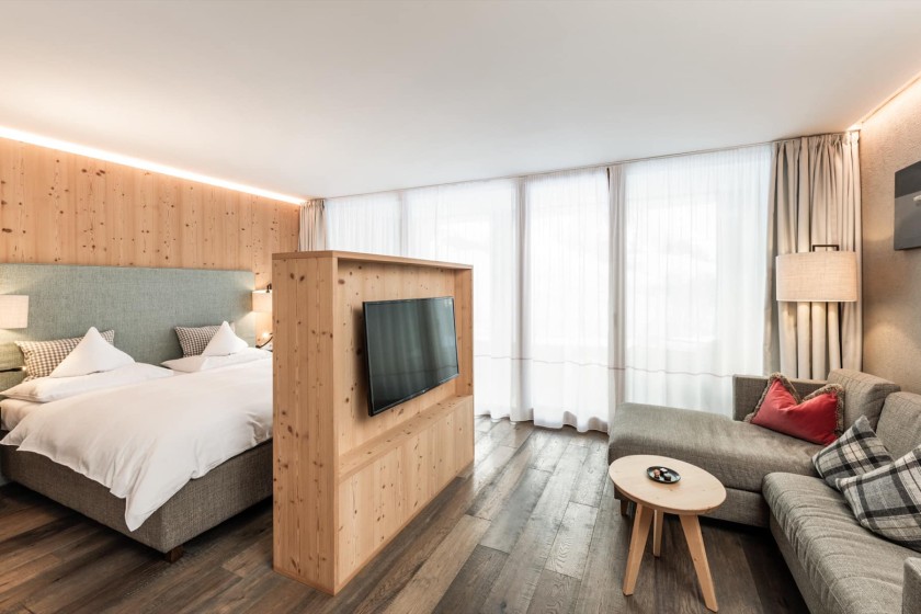 Letto matrimoniale e divano divisi da una parete con TV