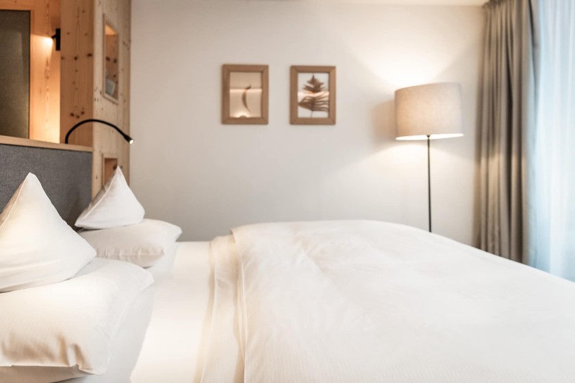 Un moderno letto d'hotel con lenzuola bianche fresche e illuminazione soffusa per il relax.