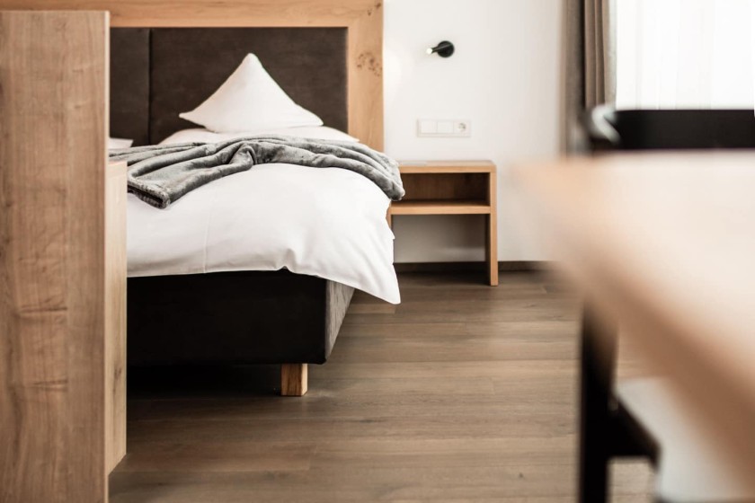 A cozy hotel bed with warm lighting and wooden decor in a modern alpine style.